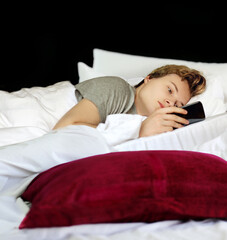 young man relaxing on her bed,using smartphone