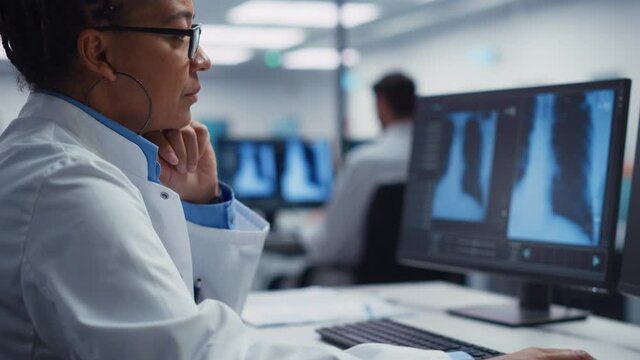 Modern Hospital Laboratory: Black Female Medical Doctor is Working on Computer Analysing Chest, Bones X-rays on Screen. Professional African American Physician Doing High-Tech Treatment Research