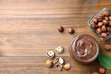 Flat lay composition with tasty chocolate hazelnut spread on wooden table, space for text