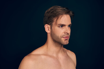 Fototapeta premium Handsome young man isolated. Portrait of shirtless muscular man is standing on dark blue background.