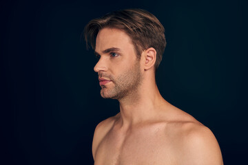 Fototapeta premium Handsome young man isolated. Portrait of shirtless muscular man is standing on dark blue background.