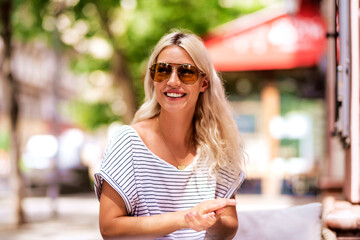 Young blond haired woman wearing sunglasses while sitting at outdoor cafe