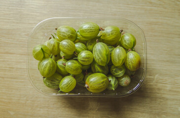 Green gooseberry in a plastic container. Organic ripe raw berries.