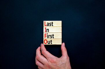 LIFO last in first out symbol. Concept words LIFO last in first out on wooden blocks. Beautiful black table black background. Businessman hand. Business LIFO last in first out concept. Copy space.