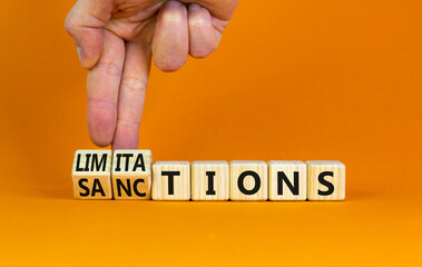 Sanctions or limitations symbol. Businessman turns cubes, changes the word sanctions to...