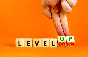 Level up or down symbol. Businessman turns cubes and changes concept words level down to level up. Beautiful orange table, orange background. Business and level up or down concept. Copy space.