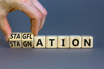Stagflation or stagnation symbol. Businessman turns cubes, changes the word stagnation to stagflation. Beautiful grey table grey background, copy space. Business stagflation or stagnation concept.