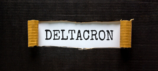 Covid-19 corona deltacron symbol. The concept word Deltacron appearing behind torn black paper. Beautiful black and white background. Medical, covid-19 corona deltacron variant concept. Copy space.