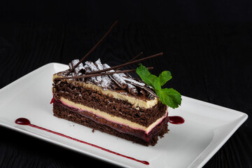 Chocolate cake decorated with mint leaves on black background