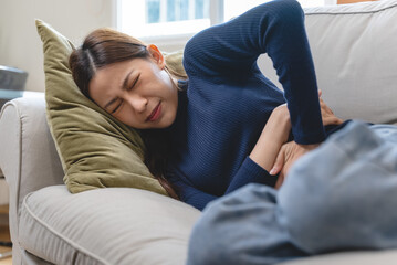 young woman gripping her stomach have abdominal pain .
