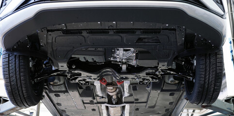 Modern car in a car service on a lift. The front of the car is shown in close-up. Bottom view. Selected focus.