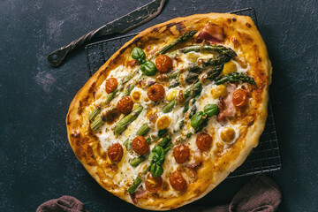 Asparagus and prosciutto pizza with mozzarella and quail eggs top view