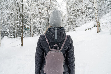 Fototapeta na wymiar Woman in winter jacket walking in snowy winter forest, snowy winter day