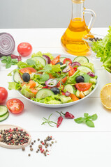 Healthy fresh vegetable salad with tomatoes, cucumbers and bell peppers in a plate on a white wooden background