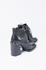 Women's boots with black genuine leather on heels isolated on a white background. photo from the side, diagonally and foreshortened from behind. Women's shoe collection 2022