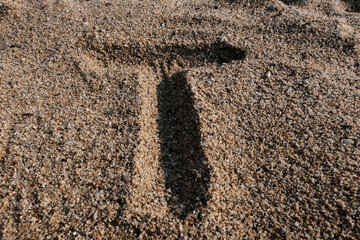 English alphabet. Sand on the beach. The letter T
