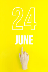 June 24th. Day 24 of month, Calendar date.Hand finger pointing at a calendar date on yellow...
