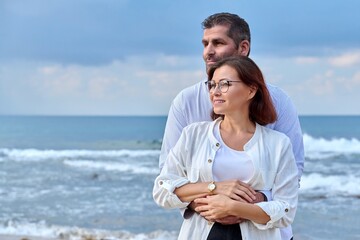 Outdoor portrait of mature couple hugging on the seashore, copy space