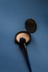 Pressed powder with makeup brush on a blue background