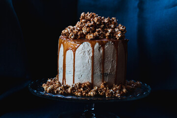 Caramel cake with popcorn on top on the dark background