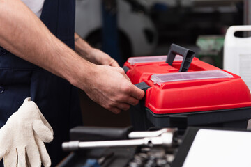 Cropped view of mechanic unlocking toolbox in garage.