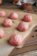 Many fresh raw meatballs on wooden board