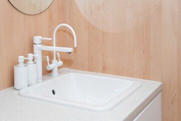 Modern white faucet and ceramic sink. Minimalist bathroom interior details