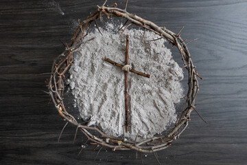 crown of thorns around a simple wood cross on a mound of ashes