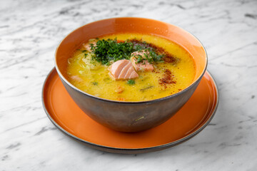 Cream cheese and fish with seafood soup. First course in a festive plate on a marble background. Restaurant banquet menu.