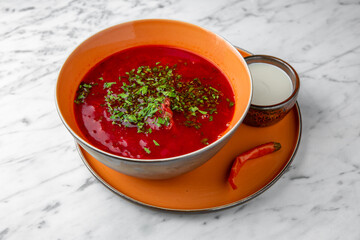 Red beet borsch in a festive plate on a marble background. Restaurant banquet menu.