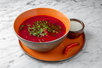 Red beet borsch in a festive plate on a marble background. Restaurant banquet menu.