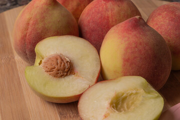 Tasty and colorful peaches (Prunus persica, scientific name in Latin) on wooden board. Selective focus.