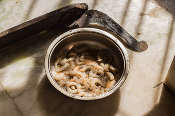 bowl of raw shrimp and indian household cutter boti kept together for dressing of seafood before cooking. photo in natural light.