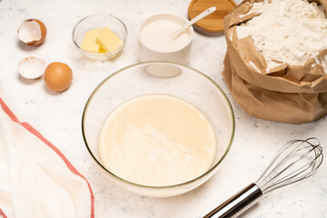 the process of making dough for pancakes with ingredients on a light table, eggs and flour are whipped with a mixer