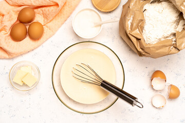 the process of making dough for pancakes with ingredients on a light table, eggs and flour are whipped with a mixer