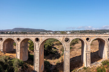 Obraz premium The stone bridge of Katouni in Kythira Greece with arches and round openings, sunny day.
