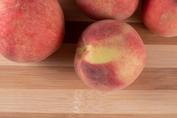 Tasty peaches (Prunus persica, in Latin), on wooden board, on rustic wooden table. Selective focus. Top view.