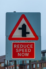 Obraz premium Staggered Junction And 'Reduce Speed Now' Road Sign 