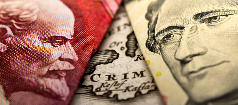 An antique map showing Crimea in between a close-up of a Russian ruble banknote - figuring Lenin - and a 10 US dollar banknote