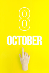 October 8th. Day 8 of month, Calendar date.Hand finger pointing at a calendar date on yellow background.Autumn month, day of the year concept.