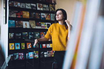 Positive young woman against bookshelves in shop