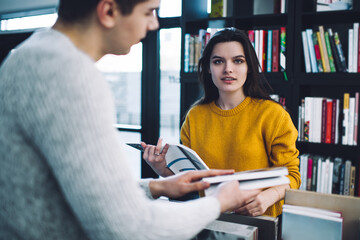 Young woman looking for interesting item in book store with friend