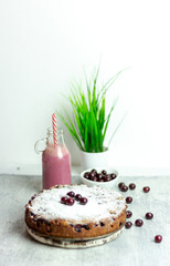 Homemade cherry pie and red cherry smoothie and sprinkled with berries on a gray table, close-up. Summer breakfast