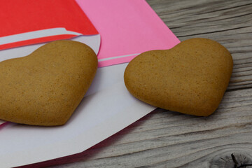 two heart shaped cookies, purple and red envelopes on a wooden rustic background. Valentine's Day, greeting card, pastry, copy space, top view, love concept, Engagement, horizontal.