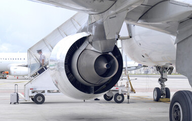 detail of airplane rear engine, pilot descending stairs in background