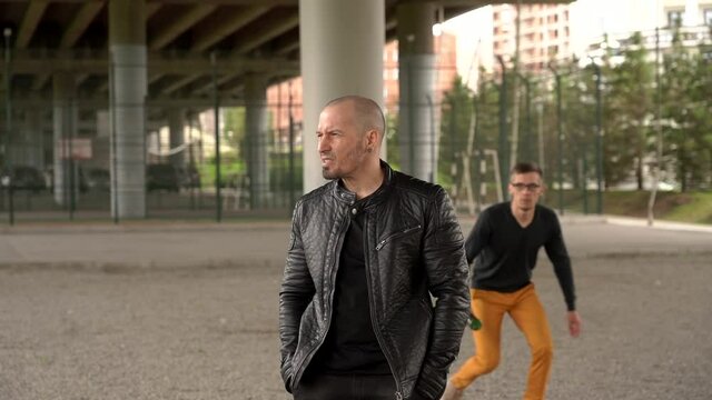 Nerd attacks a shaven-headed bandit and smashes a bottle on his head. A fight between men. Slow motion. 
