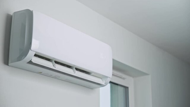 Hand adjusting temperature on air conditioner with remote control, Working air conditioner for comfort temperature in home at hot summer