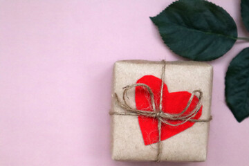 Craft gift box with red heart and craft ribbon on pink background. For celebrate. Valentines day conception.