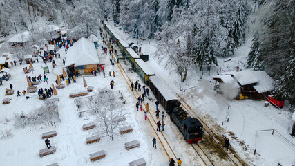 View from above of a touristic train station located in Maramures county, Romania, Shot from a low altitude in winter season. Aerial view of a narrow gauge steam train station.