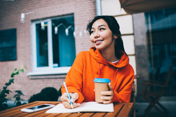 Happy ethnic woman taking notes in notepad